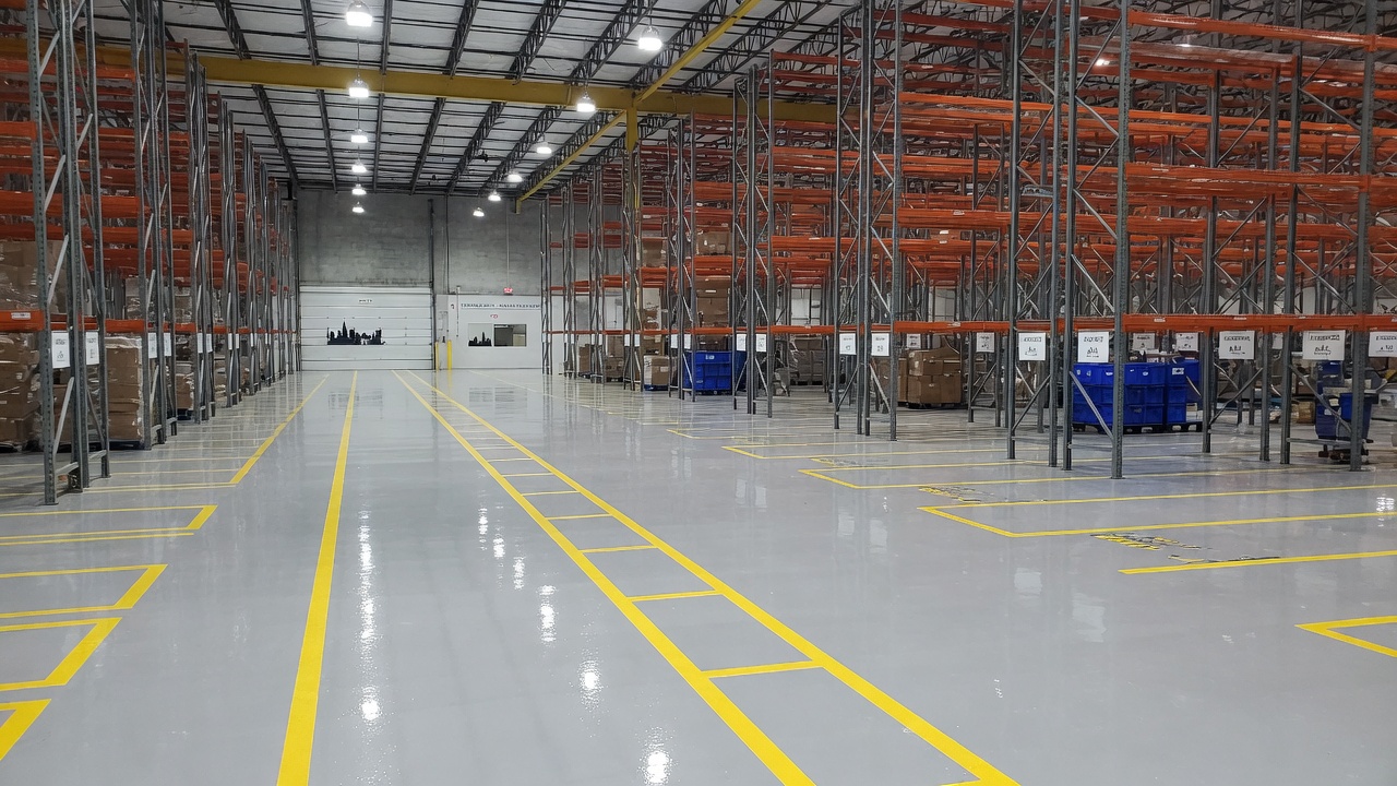 Freshly coated high-gloss epoxy floor across a large Atlanta warehouse under racking and forklift lanes