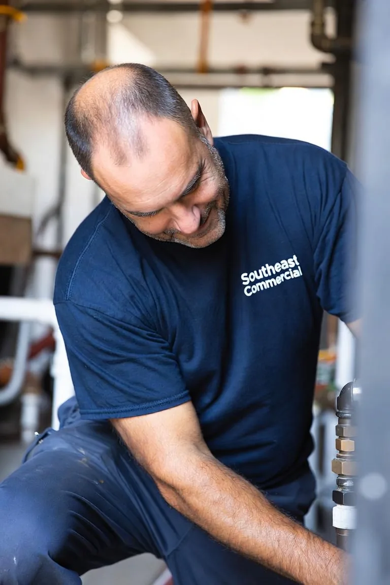 Southeast Commercial Services plumber working on pipework in an Atlanta commercial mechanical room