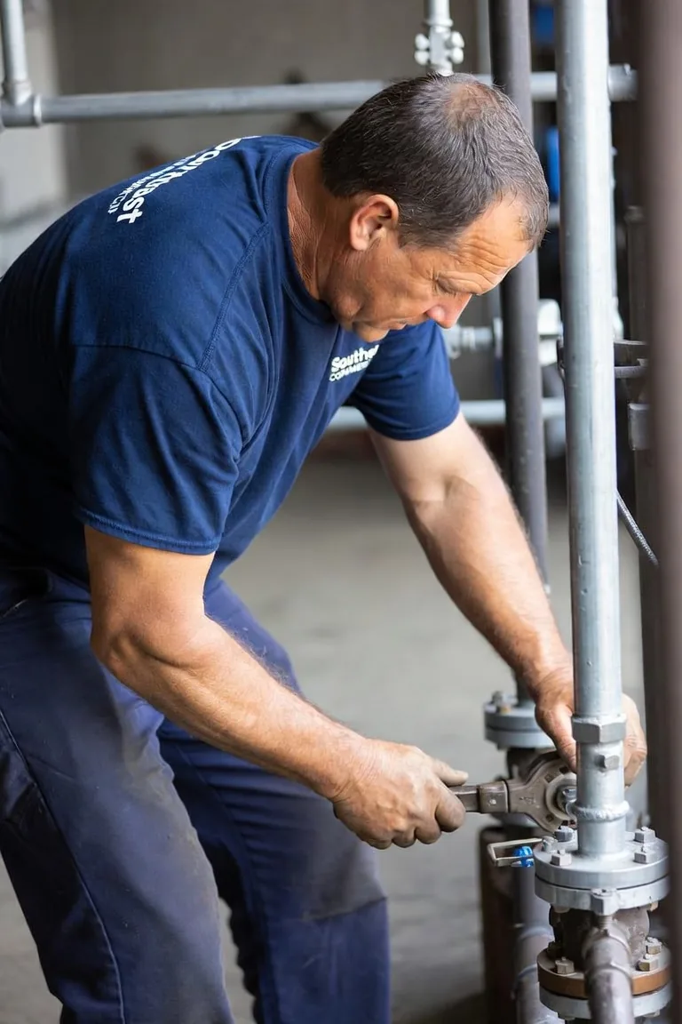 Southeast Commercial Services plumber repairing a commercial water valve and pipe riser in Atlanta